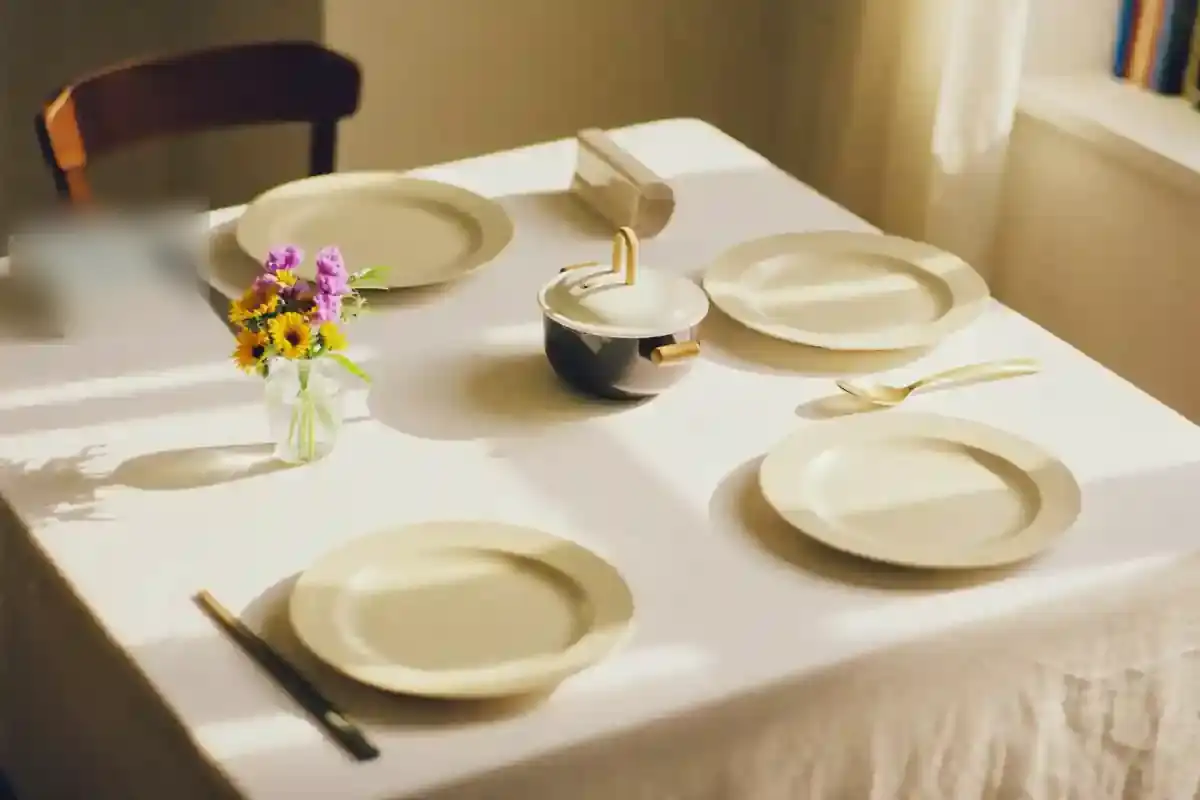 아침 볕이 드는 집, 네 사람 몫으로 차려진 밥상. 가운데 냄비와 젓가락, 작은 꽃병이 놓여 있고 사람은 없다.