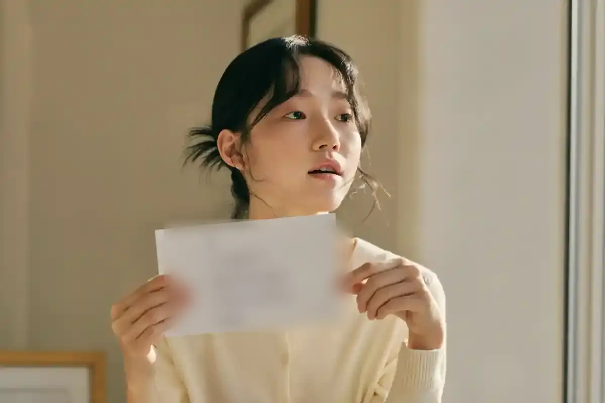 창가에 서서 백지 카드를 들고 소리 내어 말하는 여성.